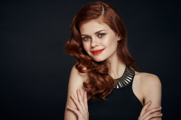 Fototapeta premium attractive red-haired woman in a black dress hairstyle dark background