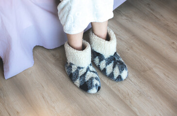 Woman is wearing Home soft warm slippers. Warm home footwear, fluffy shoes. Cold winter weather.