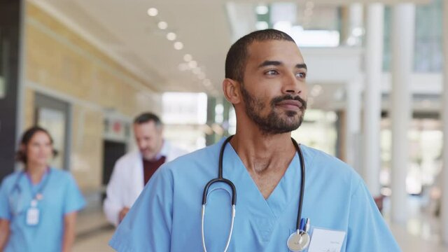 Successful mixed race nurse walking at hospital hallway