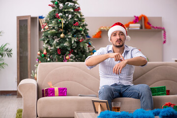 Obraz na płótnie Canvas Young man celebrating Christmas at home alone