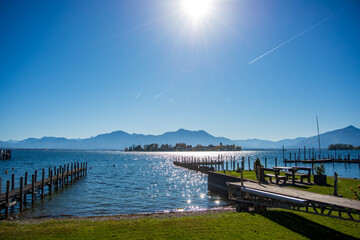 View of Fraueninsel on lake Chiemsee on a clear autumn morning with the alps in the background and contrails