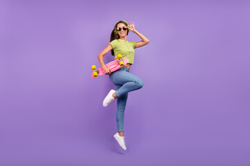 Fototapeta na wymiar Full length body size view of nice cheerful girl jumping listening pop dancing with skate isolated over purple violet color background