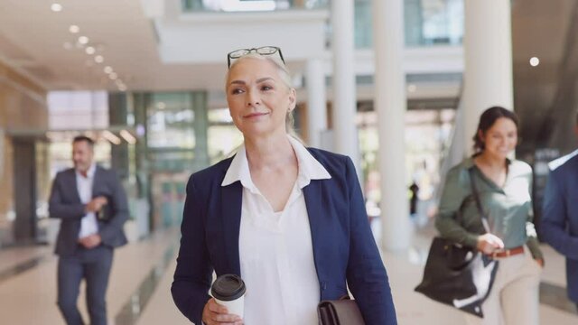Senior businesswoman looking and smiling at camera while walking