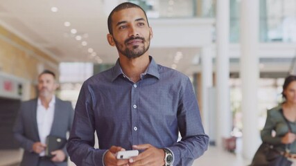 Young positive businessman thinking while walking