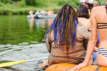 A very fat man, presumably a woman, with a haircut with dreadlocks, is rafting down the river as...