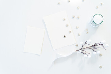 Christmas blank greeting card mockup scene. Festive winter wedding composition.Candle, Christmas decoration on white table.Flat lay, top view