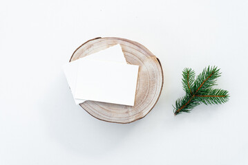 Blank greeting card or place card mockup on wooden cut round board and fir branch. Christmas scene...
