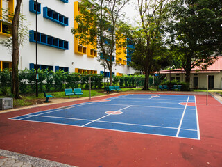 Outdoor badminton court next to a school building, in a residential neighbourhood
