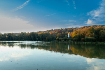 Fototapeta premium An old landing stage in a lake on a early morning in Autumn with bits of mist in the Dutch town Valkenburg surrounded by beautiful colors and reflections during sunrise
