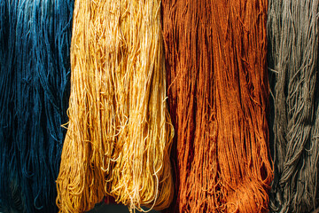 Multi colored threads hanging on bamboo. Hanging skeins of yarn background.