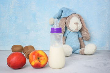 Lactation and healthy food. Breastfeeding mom's diet. Brest milk, children's toy, fruits on blue background. Copyspace