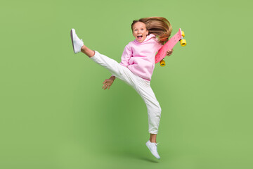 Full body photo of cool small blond girl jump with skate wear hoodie trousers sneakers isolated on...