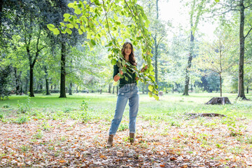 Woman holding branches while standing at park