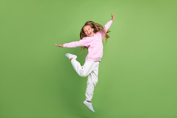 Full length photo of funny small blond girl jump wear sweatshirt trousers sneakers isolated on...