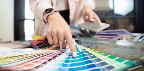 Obraz premium Banner hand of woman decorator, interior and graphic designer, architect is choosing catalogue colors ral for web project