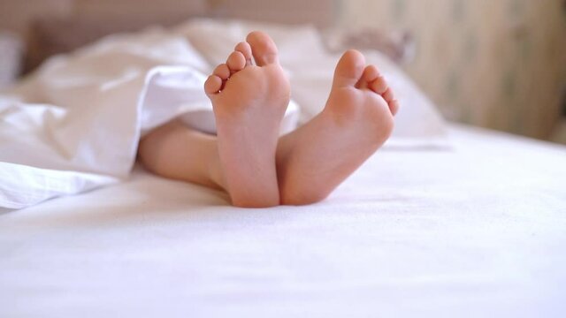 Close up barefoot baby feet lying on white bed linen. Fabric softener, cleanliness. Podology.