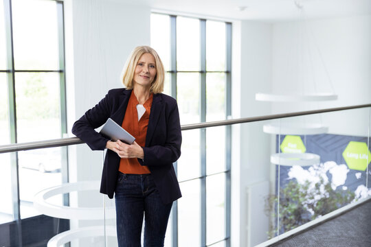 Mature female professional with digital tablet standing by railing