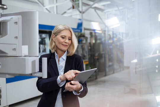 Smiling Female Professional Using Digital Tablet By Machinery In Factory