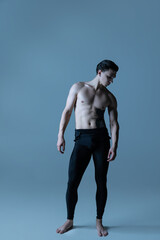 Close-up young muscled man, male ballet dancer posing isolated on old navy studio background. Art, motion, inspiration concept.