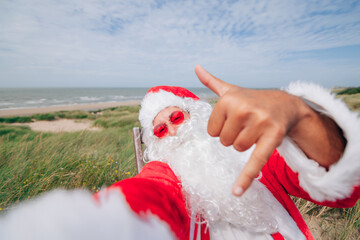 santa claus taking selfie at sea making the shaka sign - santa claus on holiday greetings from the sea