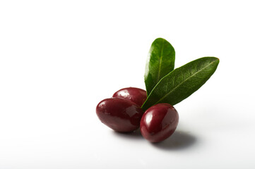 Kalamata olives with leaves soaked in olive oil over white background.