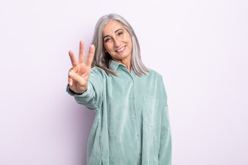 middle age gray hair woman smiling and looking friendly, showing number three or third with hand...