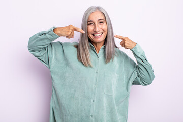 middle age gray hair woman smiling confidently pointing to own broad smile, positive, relaxed,...