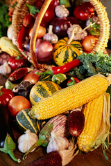 Thanksgiving Day or harvesting seasonal products concept: corn, pumpkin, tomatoes, zucchini, garlic and others. Organic grown farmer vegetables in wicker basket. High quality vertical photo