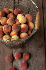 Fresh peaches fruits in basket on dark wooden rustic background, top view. Summer harvest of fruit. Still life. A group of ripe peach. Flat lay vegan food. Copy space