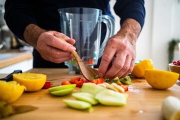 Man making smoothie with fruits at kitchen counter
