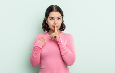 pretty teenager woman looking serious and cross with finger pressed to lips demanding silence or...