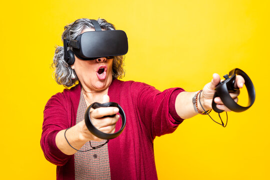 Woman holding joystick while wearing virtual reality headset against yellow background