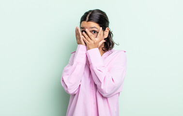 pretty teenager woman feeling scared or embarrassed, peeking or spying with eyes half-covered with...