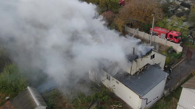 Fire in a private house. 
Strong smoke from fire from a bird's eye view. Black smoke in the sky. Drone shoots a large-scale fire. Rescuers extinguish the fire