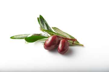 Kalamata olives with leaves soaked in olive oil over white background.