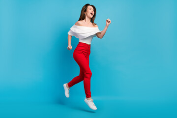 Fototapeta na wymiar Photo of impressed funky woman dressed white blouse smiling jumping running looking empty space isolated blue color background