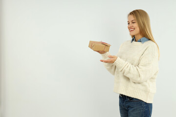 Attractive girl holds gift box on white background, space for text