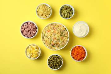Olivier salad and ingredients on yellow background