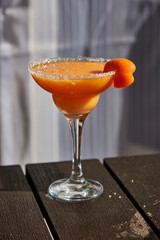 Glass with orange cocktail and apricot on the table