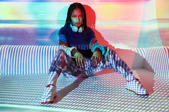 Stylish young ethnic lady looking at camera in illuminated studio