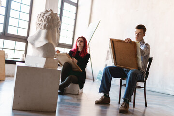 Young white student drawing plaster bust during class in art school