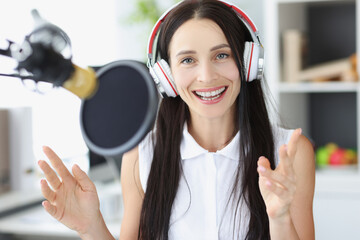 Young woman radio presenter smiling in front of microphone