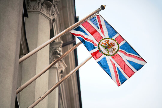 Waving Union Jack flag with the Royal Coat of Arms, the official coat of arms of the British monarch, used by British Embassies overseas