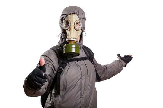 An isolated shot of a man dressed in a gas mask, a hooded jacket, a backpack, shows a gesture of okey, the other hand stretched back indicating the direction, looking into the camera. On a white