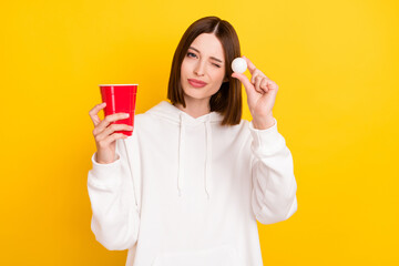 Portrait of attractive funky girl holding cup playing beer pong free time isolated over bright...