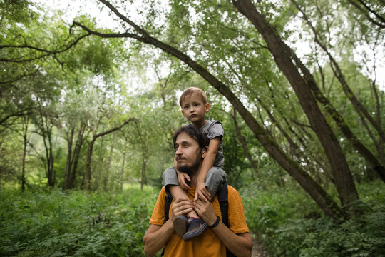 Father carrying son on shoulders while hiking in forest