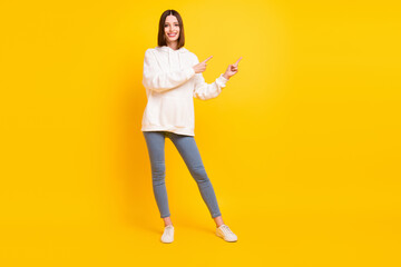 Photo of adviser lady indicate finger empty space wear white hoodie jeans footwear isolated yellow color background