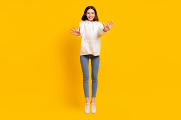 Photo of funny energetic lady jump wave palm wear white hoodie jeans shoes isolated yellow color background