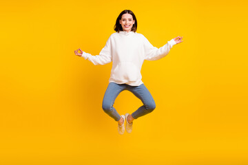 Photo of sporty lady jump yoga practice wear white hoodie jeans sneakers isolated yellow color background
