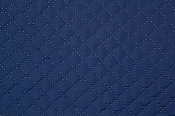 Blue quilted fabric. The texture of the blanket.	
